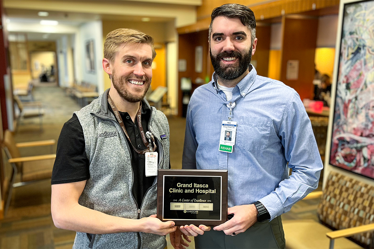 Dr. Eric Warne and Dr. Craig Close holding the ChiroCare Centers of Excellence Distinction Plaque 